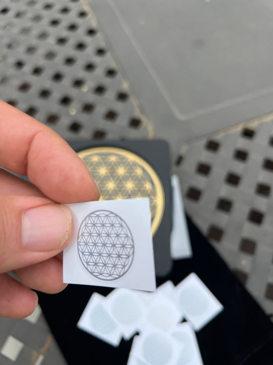 Hand holding Sacred Flower of Life patches with geometric design and multiple patches in background